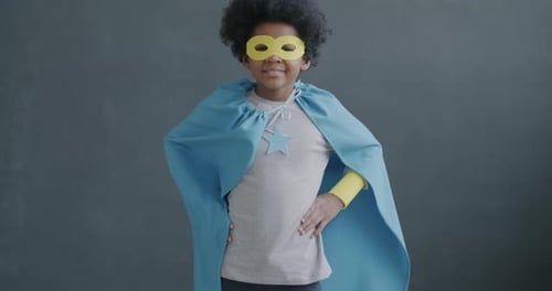 Slow Motion Portrait of Joyful African American Boy in Super Hero Costume Mask and Cape Standing on