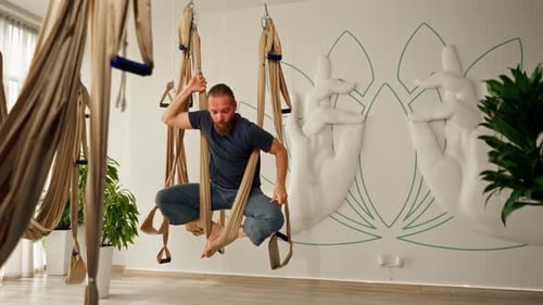 Bearded Man Practicing Aerial Yoga in Studio
