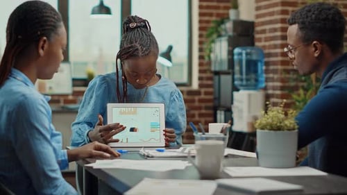 Business Team Meeting with Data Presentation on Tablet