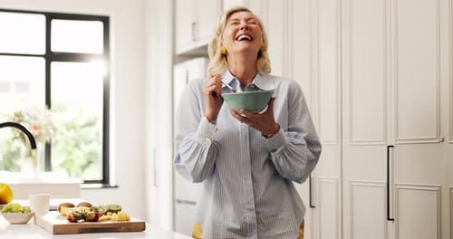 Laughing Woman Enjoys Healthy Snack in Bright Kitchen