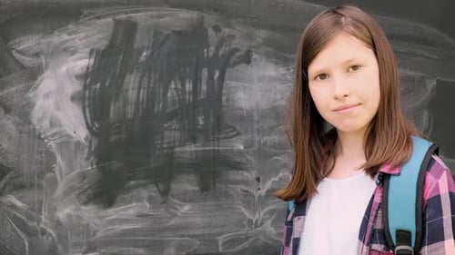 Girl with Backpack Near Chalkboard Smiles