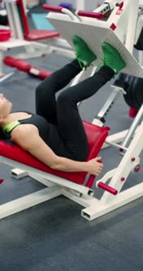 Woman Using Leg Press Machine in Gym