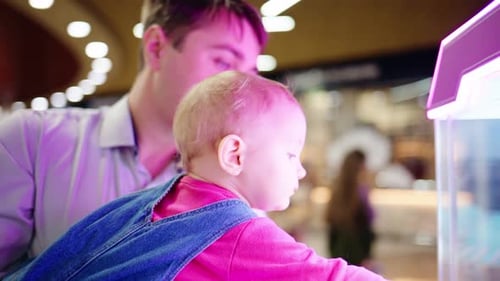 Man and Infant Gazing at Display Case