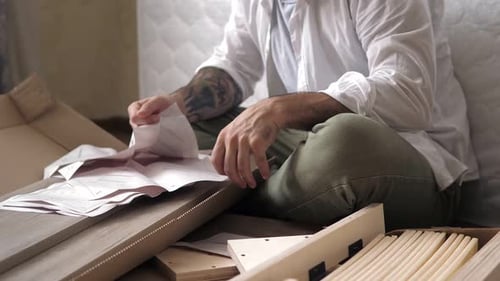 Man Assembling Furniture Reading Instructions At Home