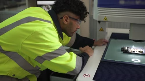 Der Mechaniker arbeitet im Forschungslabor mit elektronisch Leiterplatte und Mikroskop.