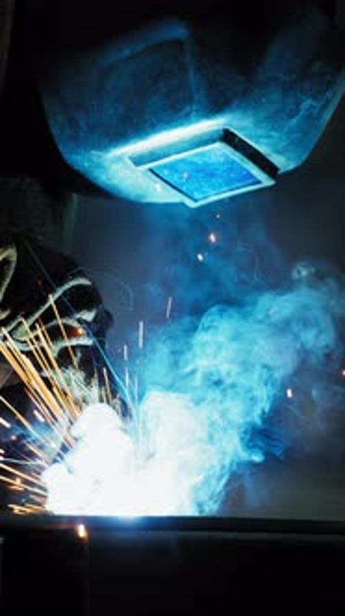 Professional Welder Working at Factory Facility Factory Workshop with a Male Technician Welding in