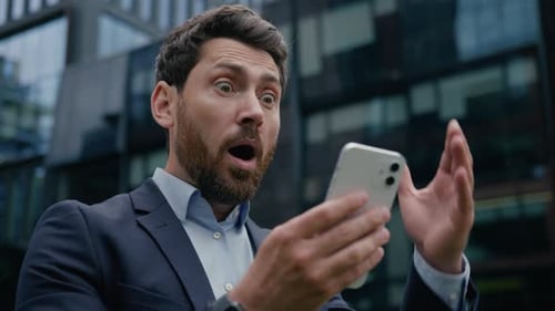 Surprised Man Reacts to News on Mobile Phone