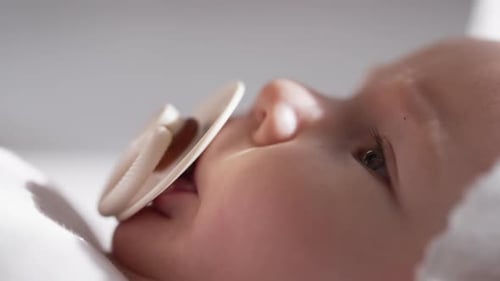 Süßes neugeborenes Mädchen, das sich mit Schnuller entspannt, entzückender Kinderpuppe, die saugt