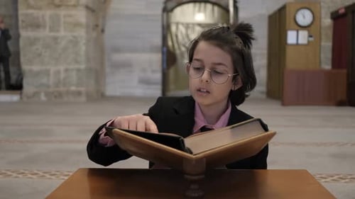 Child Reads Large Religious Book Indoors