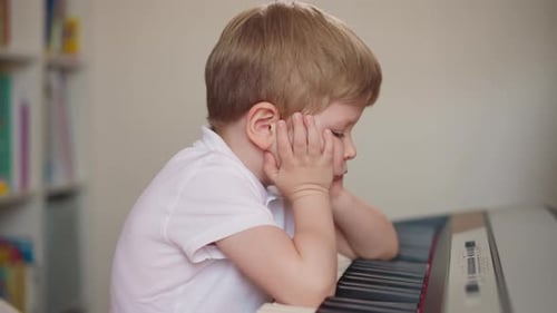 Little Boy Stops Playing Piano and Puts Elbows on Keyboard