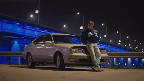 Night Blue Bridge Parking White Man Leaning on Sedan Underpass Lights Solitary Driver Reflecting