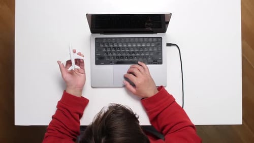 Top View Man Booking Flight Tickets Online Using Laptop and Holding Toy Airplane
