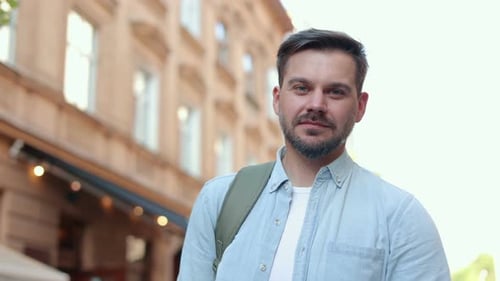 Portrait Shot of Smiling and Laughing Handsome Young Man with Backpack Walking on Street of Old Town