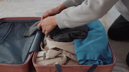 Adult Packing Luggage for Travel in Home Interior