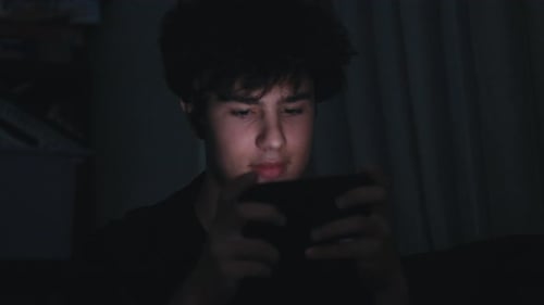 Teen Boy Concentrating on Tablet in Dark Room