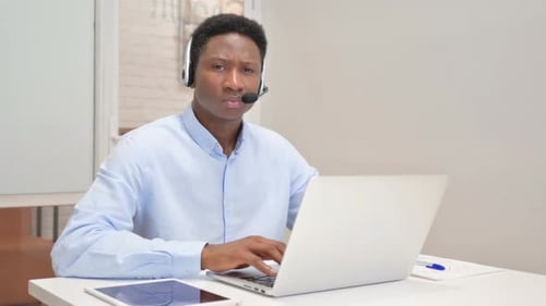 African Man with Headset Looking at Camera in Call Center
