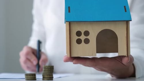 Holding a Model Home in Front of Coins