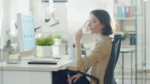 Focused Creative Woman Sitting at Her Desktop Computer in Her Office. Thinking of Problem Solving a