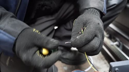 Electrician connects electrical wires with tool close up