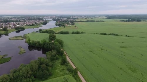 Un río que serpentea entre campos verdes y un asentamiento. Imágenes aéreas al revés