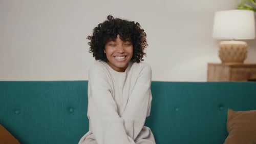 Woman Smiling and Sitting on Couch Indoors