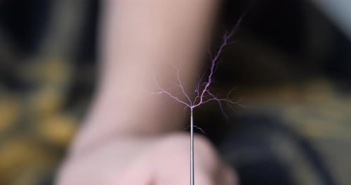 La foudre générée et les doigts d'enfants expérimentent avec un transformateur résonnant produisant une haute