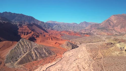 Aerial view drone flying over scenic red rocky mountains landscape with a clear blue sky.