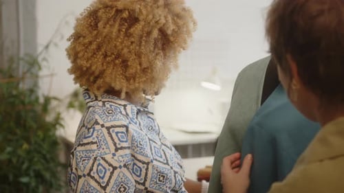 Schneiderin heftet Stoff an Schaufensterpuppe und spricht mit einer Kollegin