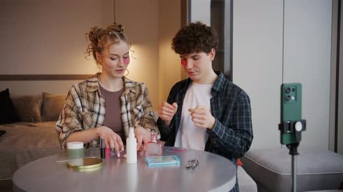 Los adultos jóvenes participan en un tutorial de maquillaje en una habitación moderna con un teléfono inteligente sobre un trípode durante una