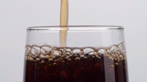Close Up Of Fresh Cola Being Poured In To The Glass On White Background