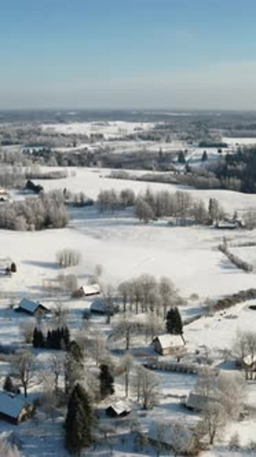 Stunning vertical aerial drone view of suburban living on a sunny, snow-covered winter morning with