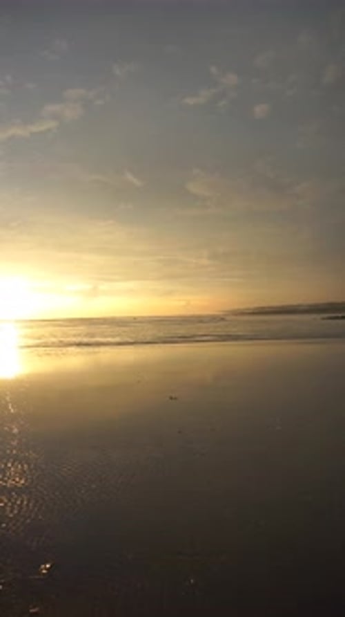 vertical video of beautiful views of the sunset on the beach with small waves, natural panorama