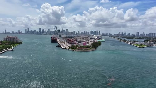 Aerial approaching shot of industrial Port of Miami, Florida with skyline in background. Sunlight wi