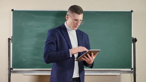 A Male Teacher Writes on a Clean Green Blackboard with a Space to Copy