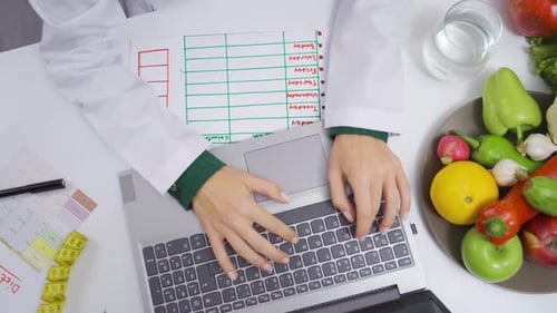 Dietician Planning Diet on Laptop with Fresh Food