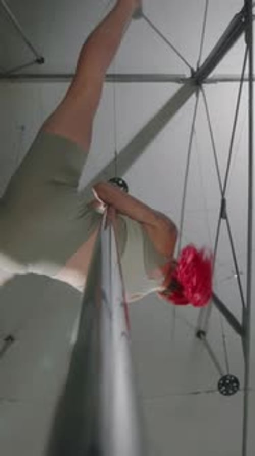 Vertical Bottom View of Red Haired Woman Pole Dancing in Studio