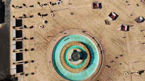 Overhead spinning shot of the Triton Fountain in Valletta, Malta. Warm day, azure blue water, people