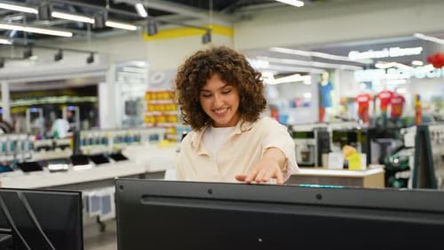 Smiling Saleswoman Showing Products on Interactive Screen in Electronics Store