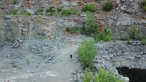 Viajante com uma mochila está caminhando perto do rio sobre o fundo de pedra no verão.