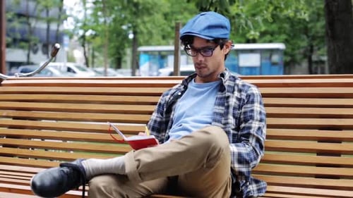 Creative hispanic man sketches ideas on a bench in the city next to his bicycle