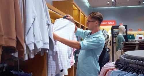 Avaliando as opções A pessoa seleciona cuidadosamente a camiseta na loja A escolha da camiseta na loja Reflects Keen