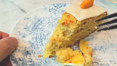 Eating a piece of carrot cake close up on a blue ceramic plate with little marzipan carrot decoratio