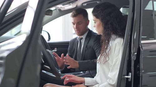 Salesman Demonstrates Car Features to Woman in Dealership
