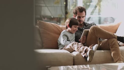 Father and Son Using Tablet Together on Couch