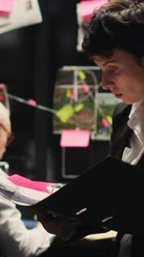 Two People Analyze Evidence in Dark Office