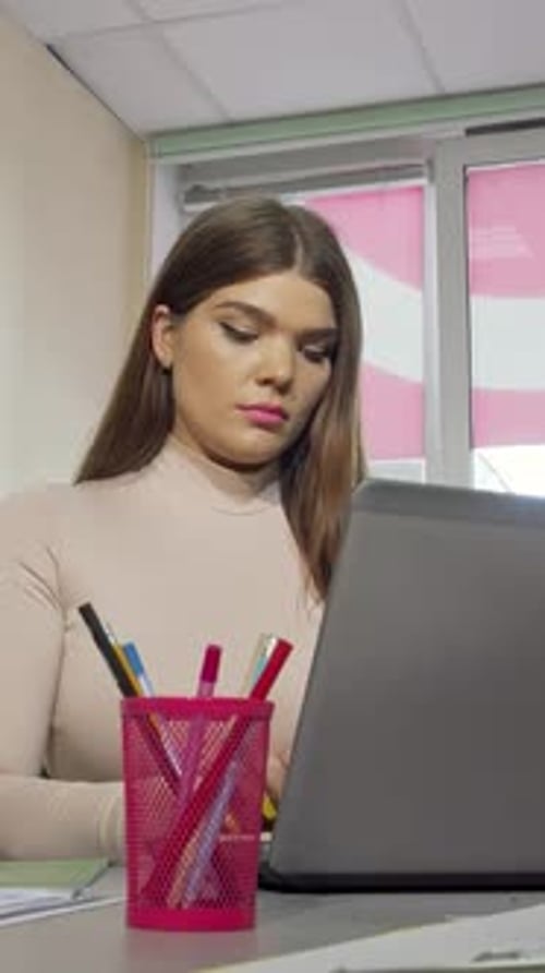 Stressed Female Student Rubbing Temples While Focused on Laptop