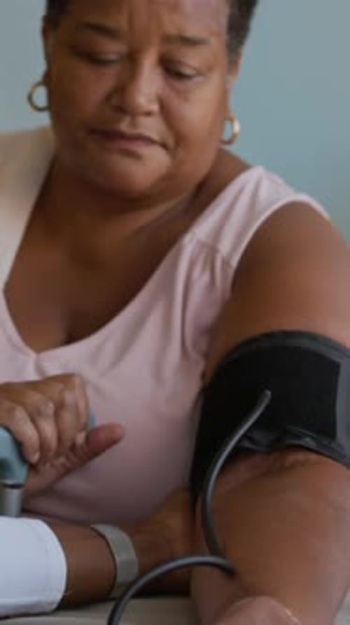 Pflegekraft misst den Blutdruck eines älteren Patienten mit Tonometer