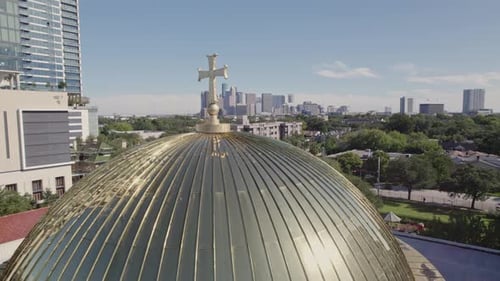 Golden Church Dome and Cross Against a Sunny City Skyline View