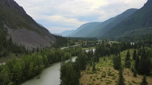 Aerial View of a Valley with a Winding River and Road Surrounded By Mountains