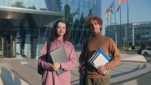 Portrait of Two Stylish Students Standing Near Modern College Architecture